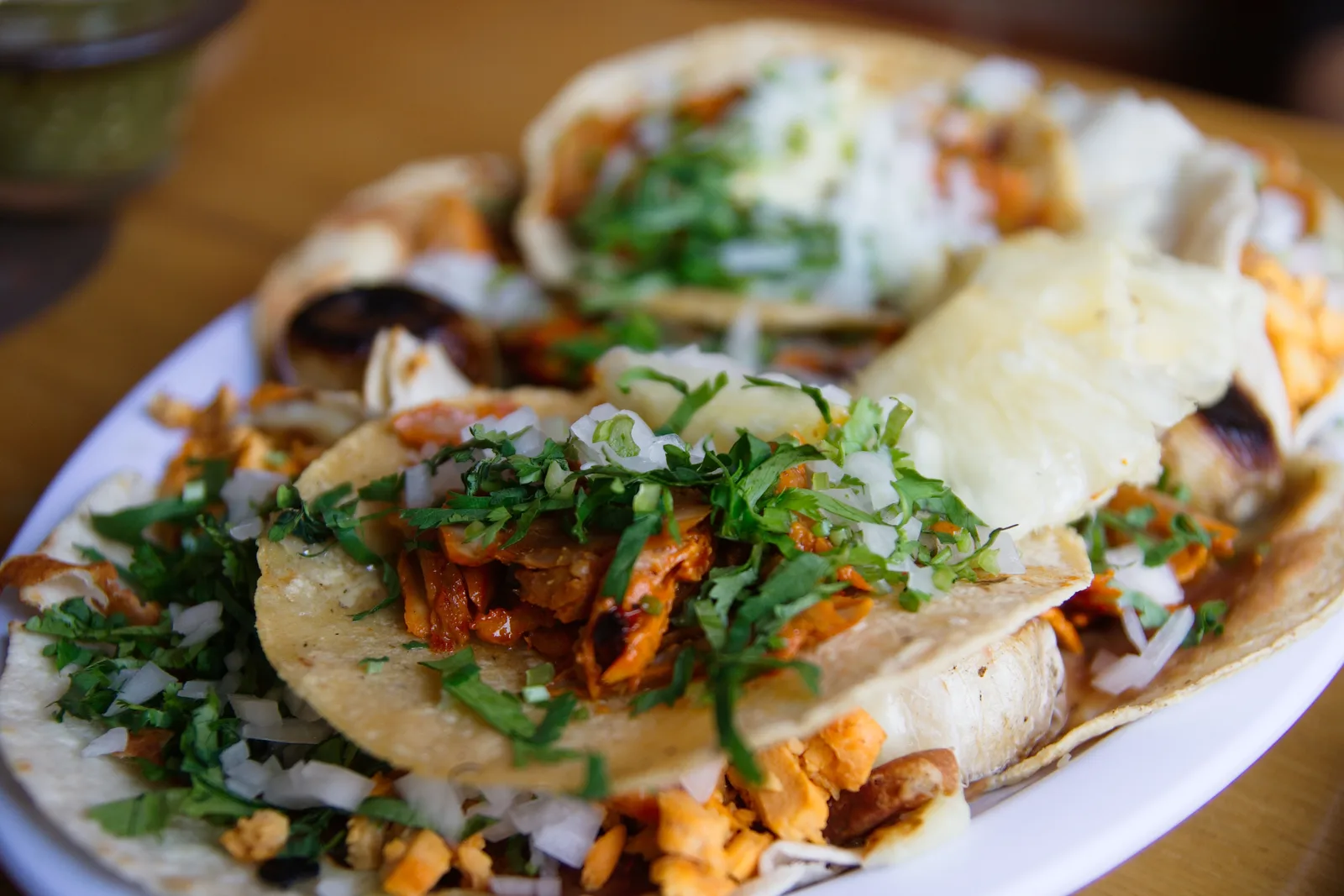 A plate of tacos al pastor topped with onion and cilantro. The photo was not taken at a Milton restaurant.