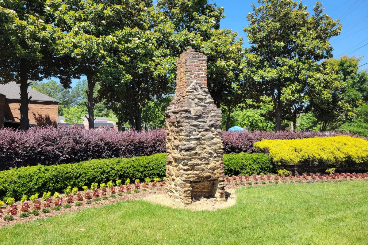 An old stone chimney kept in a landscaped bed in the Deerfield area of Milton